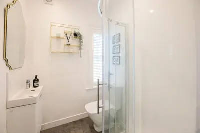 a white bathroom with a toilet and a glass shower at Seaway Cottage, Aldeburgh in Aldeburgh