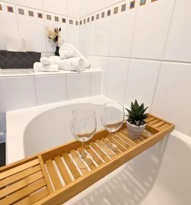 two wine glasses on a wooden tray next to a bath tub at 3-Bed, Sleeps 6, 1 Bath, Parking, WiFi in Ipswich