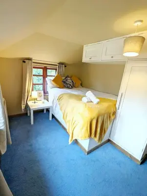 a bedroom with a large bed with a yellow blanket at 3-Bed, Sleeps 6, 1 Bath, Parking, WiFi in Shalford