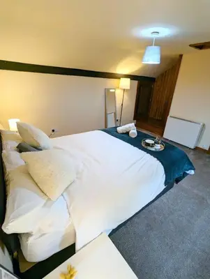 a bedroom with a large white bed with a night stand at 3-Bed, Sleeps 6, 1 Bath, Parking, WiFi in Shalford