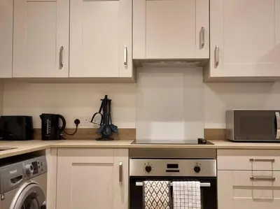 a kitchen with white cabinets and a washing machine at Modern 2bedroom House in Ipswich Suffolk in Ipswich