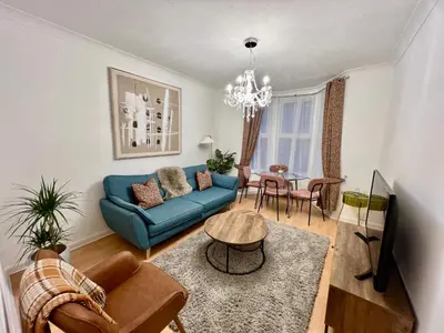 a living room with a blue couch and a table at Fig Tree Central Cambridge Apartment Walk to Colleges & River Cam in Cambridge