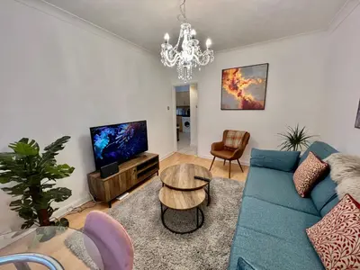 a living room with a blue couch and a tv at Fig Tree Central Cambridge Apartment Walk to Colleges & River Cam in Cambridge
