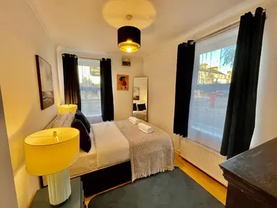 a bedroom with a bed with a yellow chair and a window at Fig Tree Central Cambridge Apartment Walk to Colleges & River Cam in Cambridge
