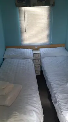 two twin beds in a room with a window at Holiday Caravan in Clacton-on-Sea