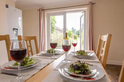 a table with two plates of food and wine glasses at Grove Farm Bungalow and Annexe, Dallinghoo in Woodbridge
