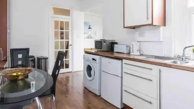 a kitchen with a table and a washing machine at Seaside private garden in Leigh-on-Sea