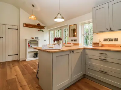 a kitchen with white cabinets and a counter top at Rookery Cottage in Saxmundham