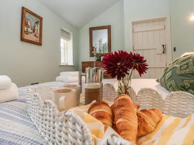 a tray of bread and croissants on a bed at Rookery Cottage in Saxmundham