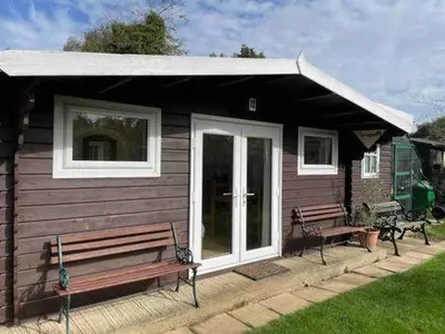 a small house with two benches in front of it at Ferncroft Garden Studio in Histon