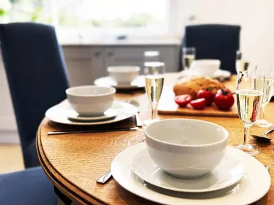 a wooden table with white bowls and plates on it at Dell View by The Suffolk Cottage Collection in Bentley
