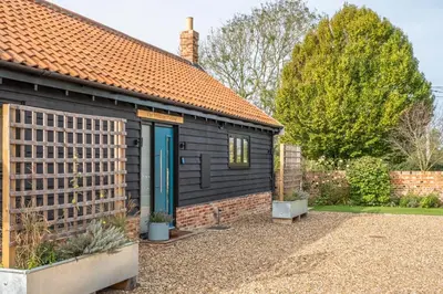 a black shed with a blue door in a yard at Large immaculate rural conversion - The Milking Parlour in Ipswich