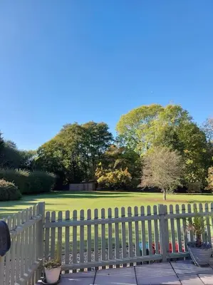 a white picket fence in front of a green yard at Woodpeckers - Alresford Essex in Alresford