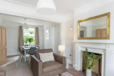 a living room with a chair and a mirror over a fireplace at Victorian 2 Bedroom Home near the river Cam in Cambridge