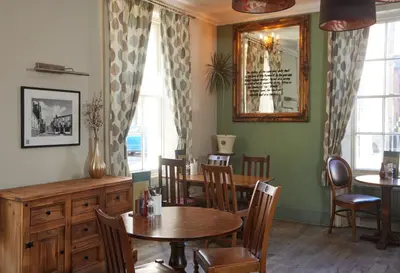 a dining room with a table and chairs and a mirror at Lamb Hotel by Greene King Inns in Ely