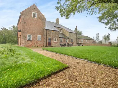an old brick building with a grass yard at Abbey Barn Farmhouse in Marham