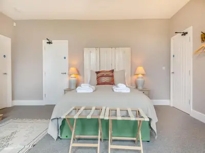 a bedroom with a large bed with two chairs at Abbey Barn Farmhouse in Marham