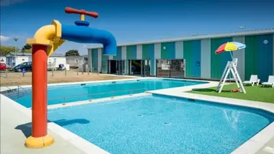 a pool with a water slide in front of a building at PET FREE family mobile Home sleeps 8 with large secured decking Sea wick holiday park in Clacton-on-Sea