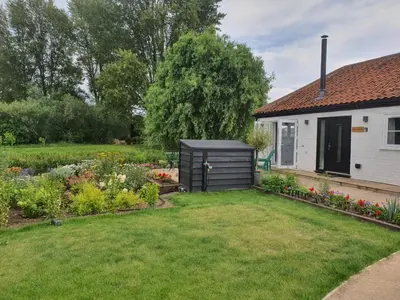 a garden with a black shed in front of a house at River Cottage in Stoke Ferry