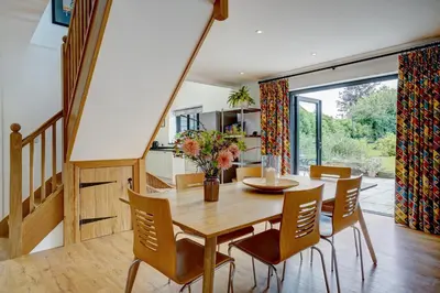 a dining room with a wooden table and chairs at Contemporary Barn Harleston Norfolk in Harleston