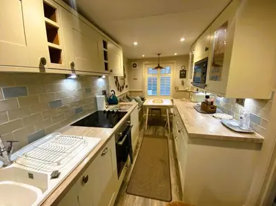 a large kitchen with white cabinets and a sink at Beautiful Immaculate Aldeburgh cottage, free parking, sunny outdoor space, dog friendly - perfect for Spring seaside escapes in Aldeburgh