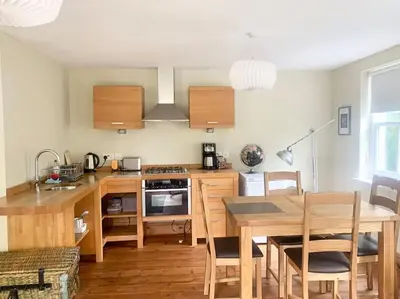 a kitchen with a wooden table and a dining room at Delightful Ely house Bright and warm with cathedral view in Ely