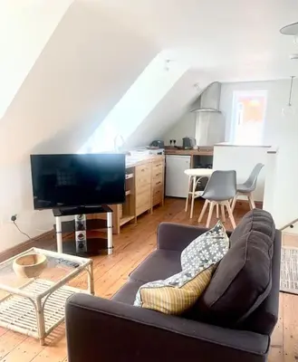 a living room with a couch and a kitchen at Delightful Ely house Bright and warm with cathedral view in Ely