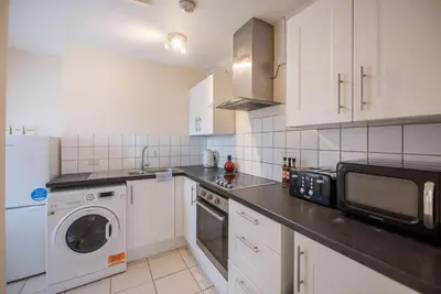 a kitchen with white cabinets and a washer and dryer at 1 & 2 Abbey Mews, Leiston in Leiston