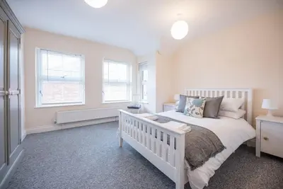 a bedroom with a white bed and two windows at 1 & 2 Abbey Mews, Leiston in Leiston