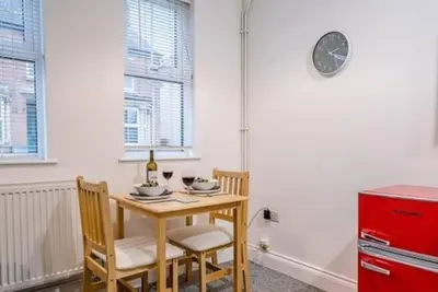 a dining room table with two chairs and a red refrigerator at 1 & 2 Abbey Mews, Leiston in Leiston