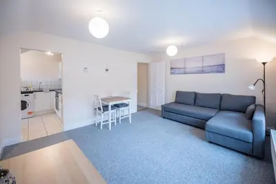 a living room with a blue couch and a kitchen at 1 & 2 Abbey Mews, Leiston in Leiston