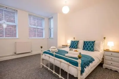a bedroom with a large bed with blue pillows at 1 & 2 Abbey Mews, Leiston in Leiston