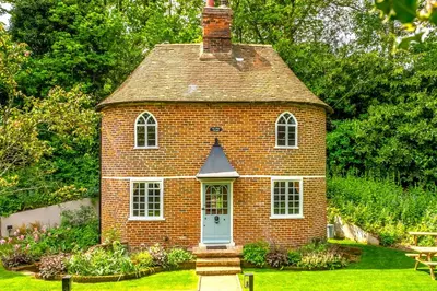 a small brick house with a blue door in a yard at A fairy-tale luxurious cottage - The Tea Caddy in Colchester