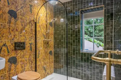 a bathroom with a shower with a toilet and a window at A fairy-tale luxurious cottage - The Tea Caddy in Colchester