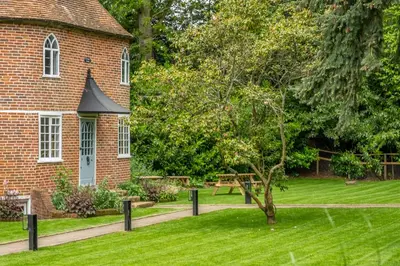 a brick building with a tree in the yard at A fairy-tale luxurious cottage - The Tea Caddy in Colchester
