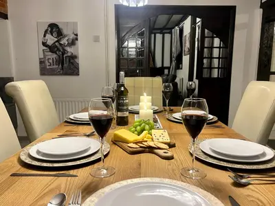 a wooden table with glasses of wine and food on it at Duchess Apt 2 Modern 3Bedroom Apartment in Colchester Ideal for Long Stays, Relocations, Contractors, Secure Parking, WIFI in Colchester