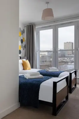 a bedroom with two beds and a large window at Jade Apartments Basildon in Basildon
