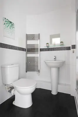 a white bathroom with a toilet and a sink at Jade Apartments Basildon in Basildon