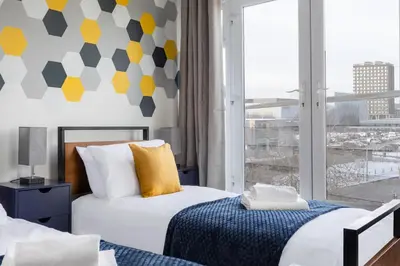a bedroom with two beds and a large window at Jade Apartments Basildon in Basildon