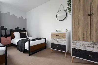 a bedroom with a bed and a dresser and a mirror at Jade Apartments Basildon in Basildon