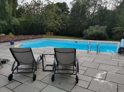 two chairs sitting in front of a swimming pool at The Woodpeckers - Alresford Essex in Alresford