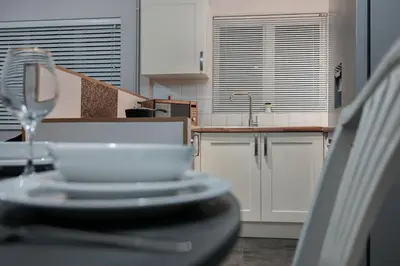 a kitchen with white cabinets and a sink and a wine glass at Hurrell House in Boreham