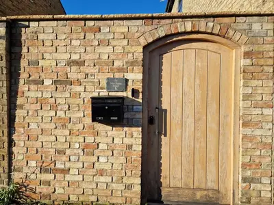 a brick wall with a wooden door on it at The Old Hay Store, Ely in Ely