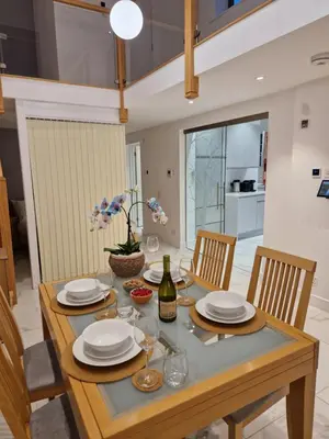 a dining room table with plates and a bottle of wine at The Old Hay Store, Ely in Ely