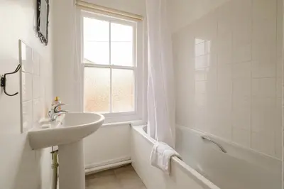 a white bathroom with a sink and a window at 41 Eastward Ho in Leiston