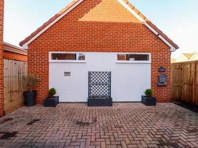 a garage with a white garage door and a brick building at Little Haven in Frinton-on-Sea