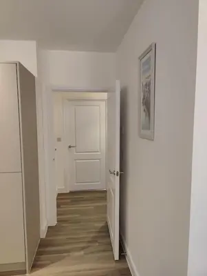 an empty hallway with a white door and wooden floors at 2 bedroom en-suite apartment in Basildon, Essex (Enjoy the simple things in life) in Laindon