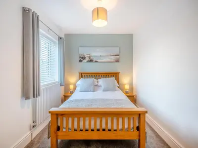a bedroom with a wooden bed and a window at Coastal Gem in Clacton-on-Sea