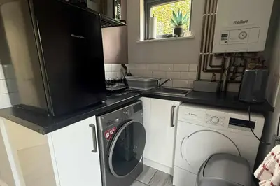 a kitchen with a washing machine and a microwave at 1 Bed Sleeps 2 with Private Garden in Harlow
