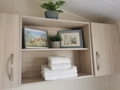 a cabinet with towels and pictures in a bathroom at Cosy 3 Bedroom Beachfront Getaway in Mersea in West Mersea